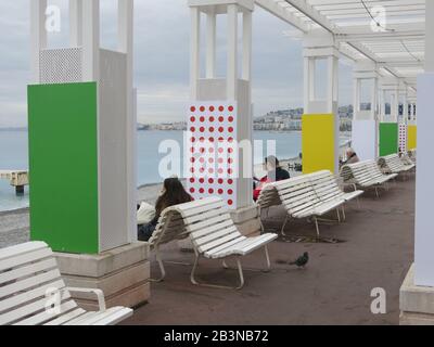 Une journée grise au début du mois de mars et il n'y a pas beaucoup de gens assis sur les sièges dans les abris sur le front de mer à la Promenade des Anglais, Nice. Banque D'Images
