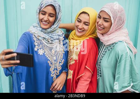 Joyeuses filles musulmanes prenant selfie avec un appareil photo pour smartphone mobile en plein air - jeunes amis arabes faire des photos pour le réseau de médias sociaux Banque D'Images