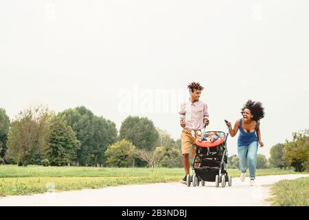 Heureux famille africaine s'amuser ensemble dans un parc public - Noir mère père et fille de bébé bénéficiant d'une belle piscine en plein air du temps Banque D'Images