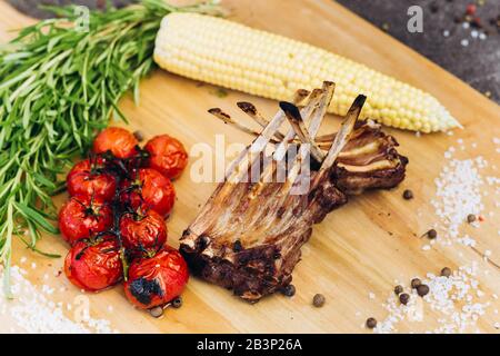 Côtes de la viande avec des légumes sur une planche en bois avec des herbes. Banque D'Images