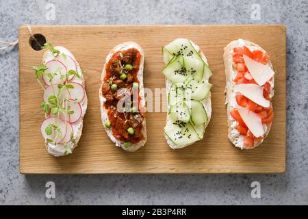 Sandwichs avec légumes, radis, tomates, concombres décorés de microgreens sur la pierre grise. Vue de dessus. Banque D'Images