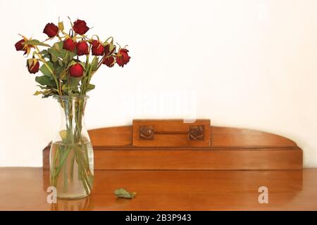 vase avec roses rouges gardées debout sur un vieux panneau latéral en bois Banque D'Images