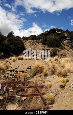 Une grille en acier et en fil métallique bloque un puits de mine dans l'ancienne zone d'extraction d'or de la réserve historique de Bendigo, Central Otago, Nouvelle-Zélande. Banque D'Images