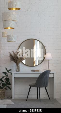 Chaise moderne en velours gris, bureau, miroir rond, lampe de table et accessoires pour la maison avec espace de copie Banque D'Images