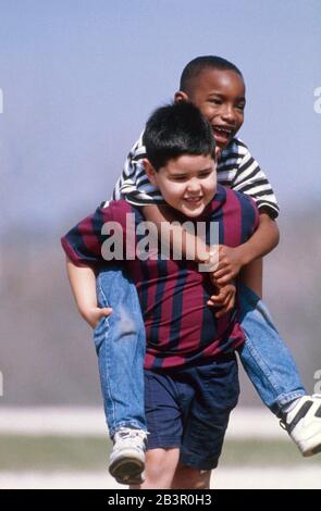 Austin Texas USA, vers 1988: Garçons afro-américains et hispaniques jouant ensemble pendant le congé sur le terrain de jeu de l'école primaire.©Bob Daemmrich Banque D'Images