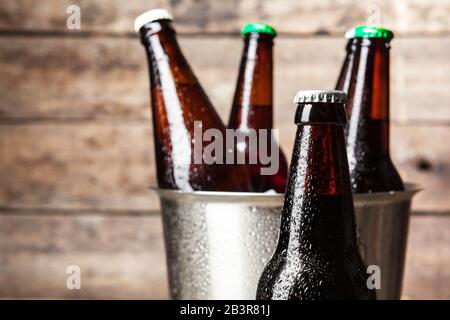 Bouteilles froides de bière dans le seau sur le fond en bois Banque D'Images