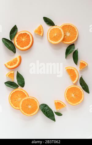 Tranches et feuilles orange stylées dans un cercle sur un fond blanc avec un espace de copie Banque D'Images