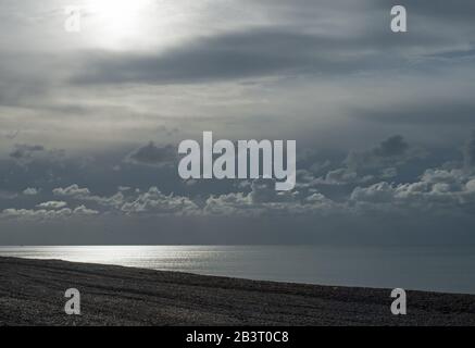 Couches de nuages au-dessus de la mer à Seaford dans l'est du Sussex, avec une faible lumière du soleil se brisant. Banque D'Images