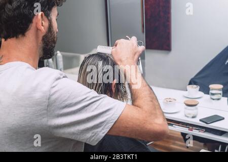 Le coiffeur de maître coupe les cheveux de femme blonde dans le salon. Gros plan de la photo. Banque D'Images