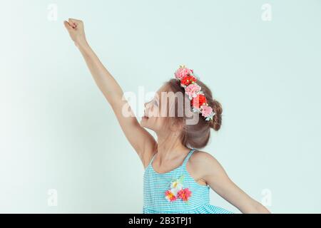 Super-héros fille en vol. Joli jeune américain caucasien heureux sourire enfant portant une robe bleue dépouillée et le bandeau floral voler à travers l'air i Banque D'Images