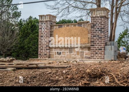 Un nouveau mur d'entrée communautaire en construction avec brique et pierre sur une vue de front de colline closeup un panneau de contreplaqué couvrant où le nom sera affiché Banque D'Images