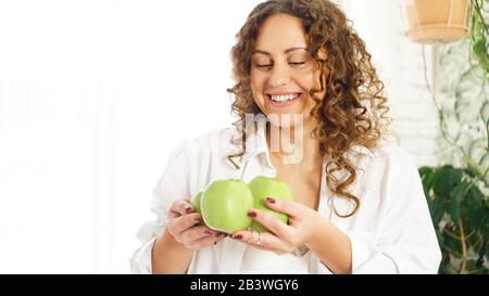Femme heureuse senior avec des cheveux frisés avec des pommes vertes. Régime. Mode de vie sain. Banque D'Images