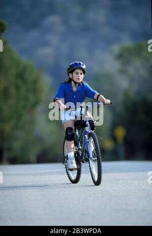 Austin Texas USA, 1998: Jeune fille panaméenne-américaine de neuf ans en toute sécurité appréciant le vélo sur une rue résidentielle vallonnée.©Bob Daemmrich Banque D'Images