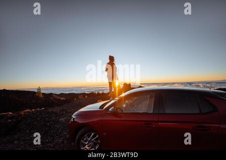 Jeune femme rocailleux paysages au-dessus des nuages, debout sur la voiture très dans les montagnes. Style de vie et concept de voyage insouciant Banque D'Images