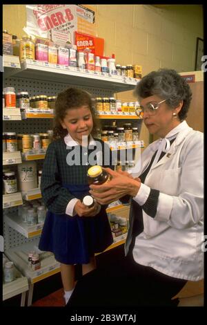 Austin Texas USA: La pharmacienne hispanique montre des bouteilles de vitamines à la petite fille.©Bob Daemmrich Banque D'Images