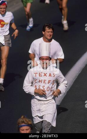 Austin Texas USA : les coureurs en équipement de course régulier entourent un coureur costumé dans un chapeau de chef, un tablier et un tee-shirt « Texas chefs Association » dans la piste annuelle Capitol 10 000 dans et autour du centre-ville.©Bob Daemmrich Banque D'Images