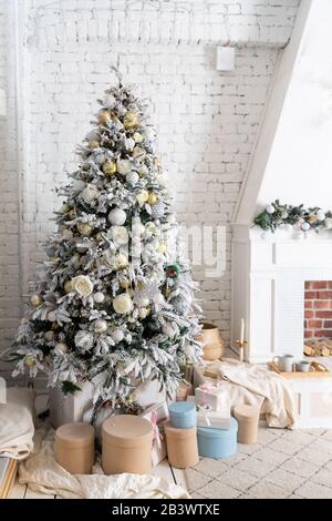 Décoration intérieure de Noël élégante, tons gris et pastel. Confort à la maison. Arbre de Noël avec des boîtes-cadeaux dénter il se tient près de la cheminée Banque D'Images