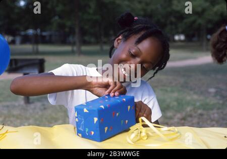 Austin Texas USA: Fille noire de neuf ans cadeau d'ouverture à sa fête d'anniversaire.* ©Bob Daemmrich Banque D'Images