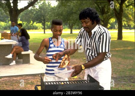 Austin Texas USA, 1987: Le père noir et son griller du poulet pour pique-niquer en famille dans le parc de la ville.©Bob Daemmrich Banque D'Images