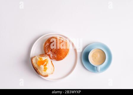 Beignet cuit maison sur une plaque en céramique blanche et une tasse de café sur un fond gris clair. Pose plate. Banque D'Images