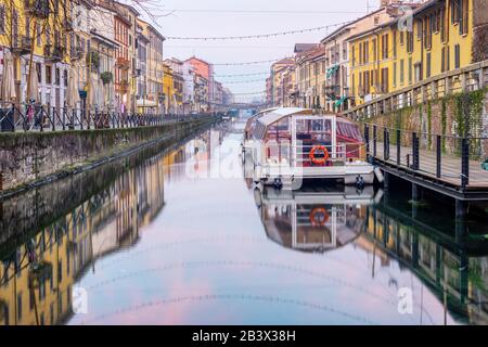 Un bateau touristique sur le canal Naviglio Grande dans la ville de Milan, en Italie, en début de matinée Banque D'Images