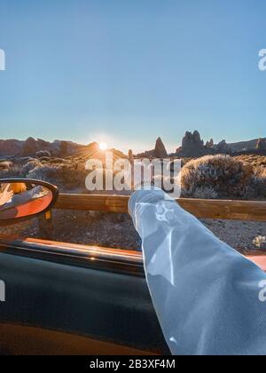 Femme pointant à la main sur la chaîne de montagnes volcaniques pendant un coucher de soleil, gros plan sur la main. Image réalisée sur le téléphone portable Banque D'Images