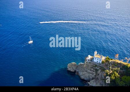 Le bateau à moteur et le yacht blanc naviguent près d'une maison lumineuse à Portofino, en Italie. Un phare est situé sur la colline près d'un bord de mer. Banque D'Images