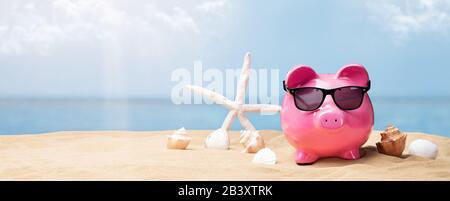 Piggy Bank Rose Avec Lunettes De Soleil Noires Sur La Plage Banque D'Images