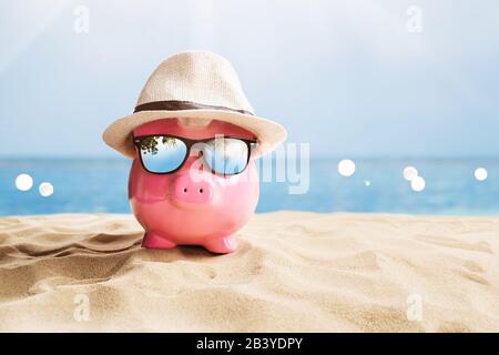 Piggy Bank Rose Avec Lunettes De Soleil Noires Sur La Plage Banque D'Images