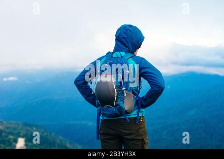 Fille dans une veste bleue avec une capuche et un sac à dos de ville dans les montagnes de l'Adygea, Russie Banque D'Images