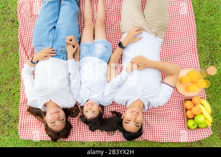 Famille des adolescents asiatiques bonne vacances pique-nique moment dans le parc avec père, mère et fille allongé sur tapis et sourire à heureux passer des vacances togerte Banque D'Images