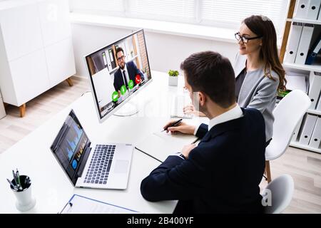 Deux jeunes gens d'affaires la conférence vidéo sur ordinateur à l'Office de Tourisme Banque D'Images