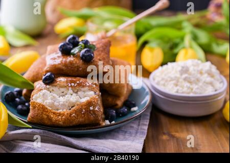 Crêpes fines avec fromage cottage et fraises. Concept de petit déjeuner traditionnel sain. Cuisson pour un carnaval russe traditionnel au printemps, Maslenitsa. Espace de copie. Banque D'Images