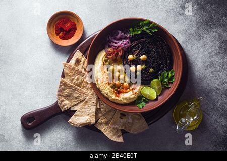 un bol de houmous, de chou violet cuit et d'oignon rouge mariné avec une tortilla et du paprika fumé Banque D'Images