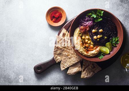 un bol de houmous, de chou violet cuit et d'oignon rouge mariné avec une tortilla et du paprika fumé Banque D'Images