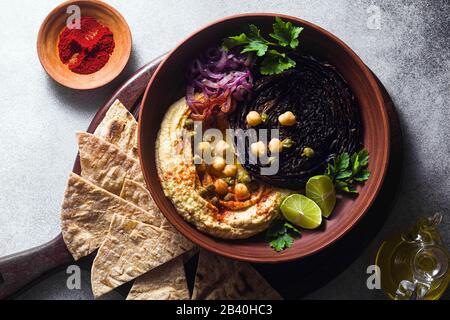 un bol de houmous, de chou violet cuit et d'oignon rouge mariné avec une tortilla et du paprika fumé Banque D'Images