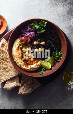 un bol de houmous, de chou violet cuit et d'oignon rouge mariné avec une tortilla et du paprika fumé Banque D'Images