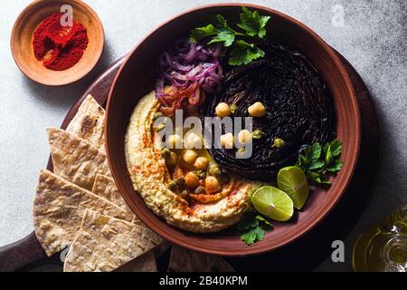 un bol de houmous, de chou violet cuit et d'oignon rouge mariné avec une tortilla et du paprika fumé Banque D'Images