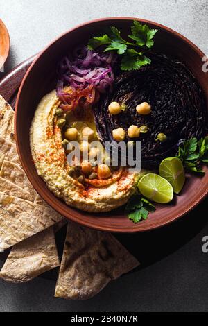 un bol de houmous, de chou violet cuit et d'oignon rouge mariné avec une tortilla et du paprika fumé Banque D'Images