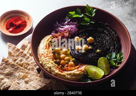 un bol de houmous, de chou violet cuit et d'oignon rouge mariné avec une tortilla et du paprika fumé Banque D'Images