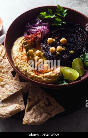 un bol de houmous, de chou violet cuit et d'oignon rouge mariné avec une tortilla et du paprika fumé Banque D'Images