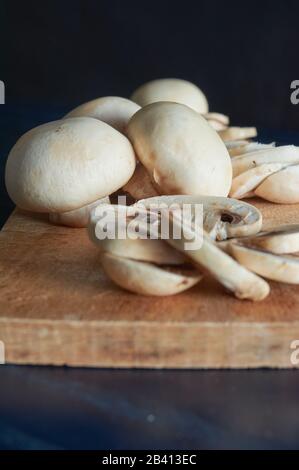 entier et tranché ​​mushrooms, sur planche en bois, sur fond bleu Banque D'Images