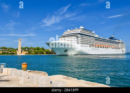 Un immense bateau de croisière tire près du monument Des Marins dans le port de croisière et le port de Brindisi, en Italie, dans la région des Pouilles du Sud. Banque D'Images