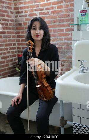 Violoniste classique dans une salle de bains classique avec une bouteille de Purell perchée au-dessus du lavabo. Banque D'Images