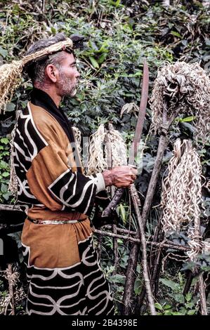 Un homme d'Ainu barbu en robe traditionnelle et tenant une épée exécute une cérémonie dans un cimetière devant un crâne d'ours décoré de copeaux de bois sur l'île d'Hokkaido dans le nord du Japon. Il n'y avait que 300 Ainu pur-sang (prononcé I-noo) vivant quand il a posé pour cette photographie historique en 1962. Depuis lors, les Ainu se sont assimilés à la société japonaise et à leurs vieux métiers d'art, les coutumes et les cérémonies ne sont maintenues en vie que dans des villages spéciaux pour les touristes. Déjà dénigrés comme des « aborigènes de poils », les Ainu ont été officiellement reconnus comme des peuples autochtones du Japon en 2008. Banque D'Images