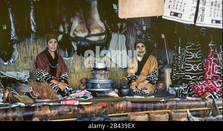 Deux femmes âgées d'Ainu en robe traditionnelle vendent des souvenirs dans un village d'Ainu sur l'île d'Hokkaido dans le nord du Japon. Un tatouage autour de sa bouche qui ressemble à une moustache est évident sur le visage d'une femme. La douloureuse tradition de la suie à frotter dans les coupes dans la peau pendant l'enfance des filles d'Ainu pour combattre les mauvais esprits a depuis été interdit par le gouvernement japonais. Les femmes étaient deux de seulement 300 Ainu pur-blooded (prononcé I-noo) encore vivant quand cette photographie historique a été prise en 1962. L'Ainu a été officiellement reconnu comme peuple autochtone du Japon en 2008. Banque D'Images