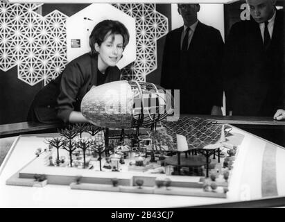 Les gens qui consultent un modèle architectural du pavillon IBM avec des arbres en acier fabriqués par l'homme et le théâtre Ovoid, conçu par Charles Eames et Eero Saarinen pour la Foire mondiale de New York de 1964. Le modèle du pavillon était probablement exposé au IBM Business Show de Manhattan au New York Coliseum, vers le 30 avril 1963. Banque D'Images