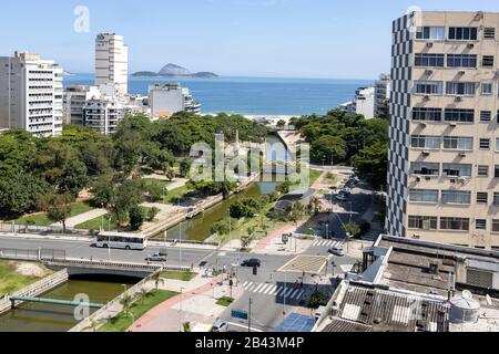 Intersection dans le quartier de Leblon à Rio de Janeiro, au Brésil, avec des bâtiments de grande hauteur et parc avec système de drainage en premier plan Banque D'Images