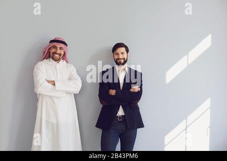 Les hommes d'affaires arabes et européens sourient sur le fond gris. Banque D'Images