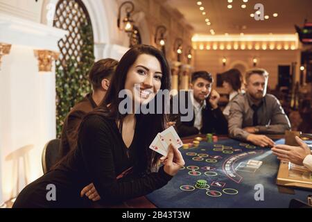 Fille avec cartes dans ses mains smiling joue au poker dans un casino. Banque D'Images